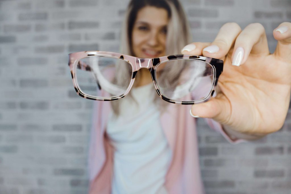 Frau hält eine Brille vor sich