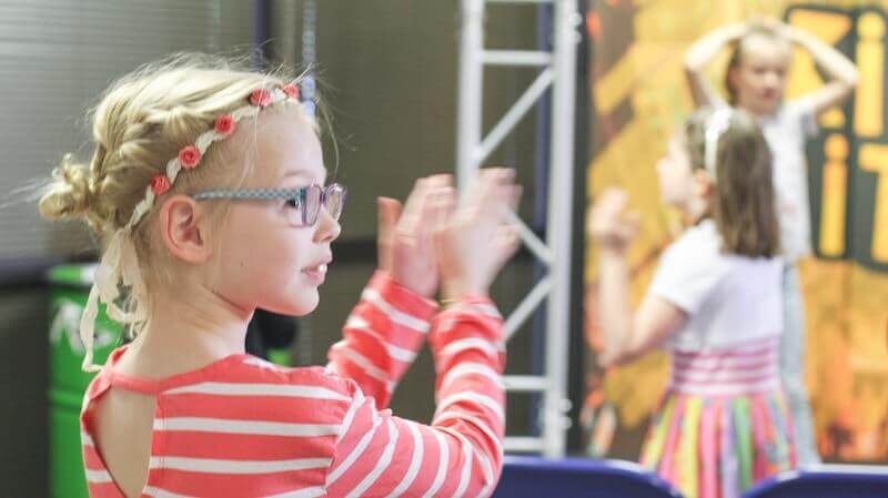 Kurzsichtigkeit bei Kindern - Mädchen mit Brille applaudiert