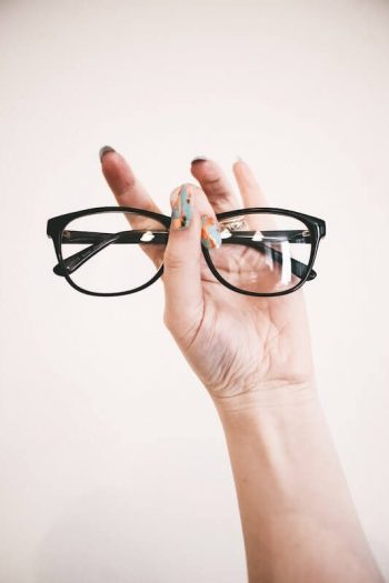 Frauenhand hält Brille hoch