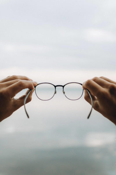 Gleitsichtbrille - rechte und linke Hand halten eine Brille an den Brillenbügeln