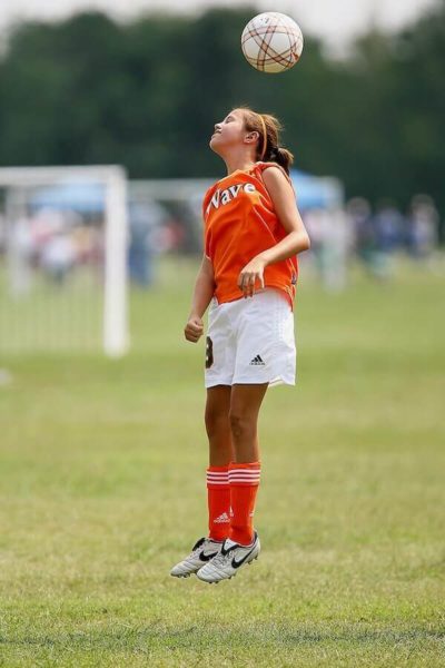 Mädchen kickt bei Fußball mit dem Kopf