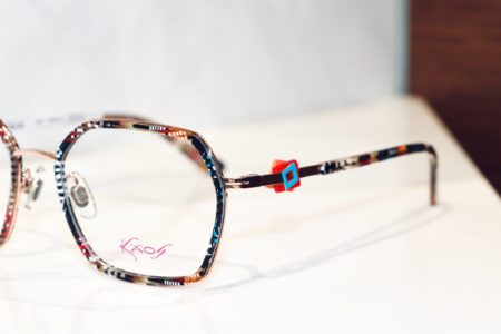 Kaos-Bille mit Detail auf Brillenbügel. Ein rotes und hellblaues Quadrat liegen übereinander