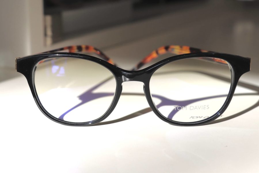 Tom Davis-Brille mit schwarzen Rahmen und orange-gestreiften Brillenbügeln