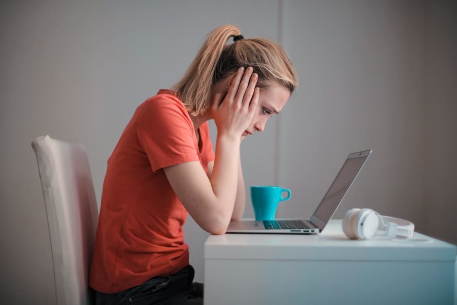 Eine Frau sitzt mit aufgestütztem Kopf vor dem Notebook. Sie hat keine Computerbrille auf.