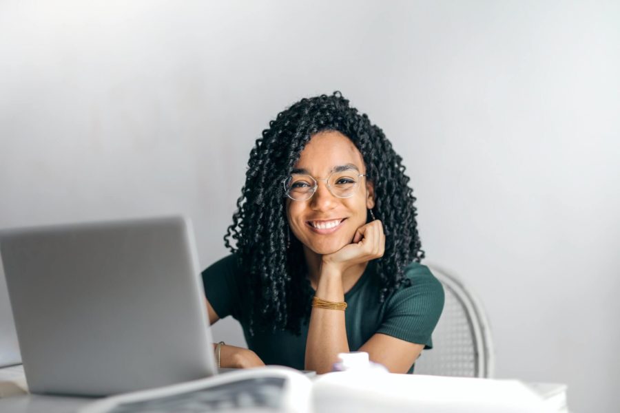 Lachende Frau mit Computerbrille vor einem Notebook am Schreibtisch