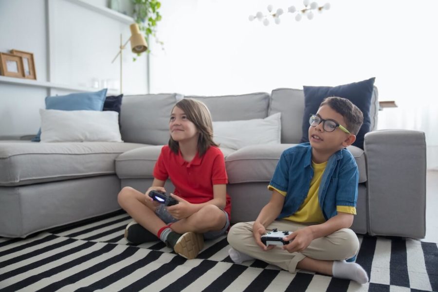 Zwei Jungs vor einem grauem Sofa beim Gaming