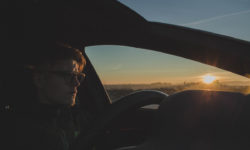 Ein Mann mit einer Autofahrerbrille auf der Nase fährt im Auto