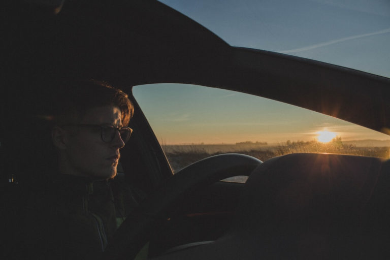 Ein Mann mit einer Autofahrerbrille auf der Nase fährt im Auto