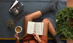 Eine sitzende Frau mit grauen Socken, die ein Buch liest