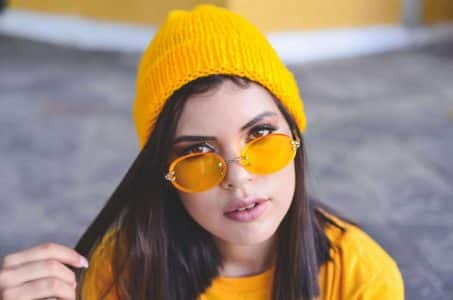 Bunte Brillen setzen Statements - Frau mit orangefarbiger Brille und orangener Mütze