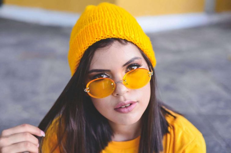 Bunte Brillen setzen Statements - Frau mit orangefarbiger Brille und orangener Mütze