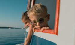 a couple of kids on a boat looking out the window