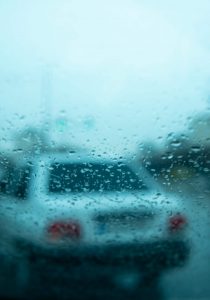 Autorfahrerbrille: Verschwommener Blick auf ein Auto bei Regen.