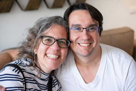 A happy couple with eyeglasses smiling together in a cozy home setting, showcasing joy and connection.
